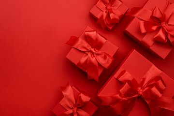 Red gift boxes with ribbons and bows on red background. Merry Christmas and Happy New Year template. Preparation for holidays. Top view. Copy space banner