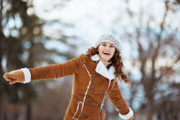 happy stylish woman rejoicing outdoors in city park in winter © Alliance