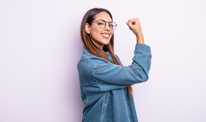 pretty hispanic woman feeling happy, satisfied and powerful, flexing fit and muscular biceps,...