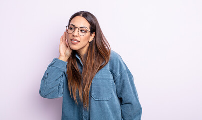 pretty hispanic woman looking serious and curious, listening, trying to hear a secret conversation...