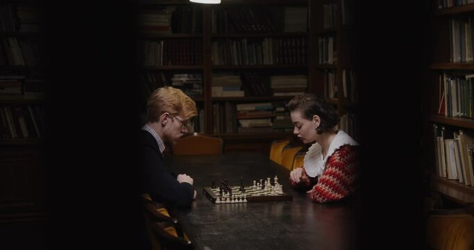 A man and a woman playing a chess game, sitting opposite each other