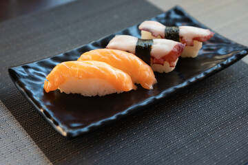Traditional japanese nigiri sushi with salmon and sushi with octopus on black plate.
