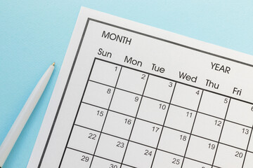 Close up pen and mounthly calendar desk for organizer. Plan or reminder on blue background.