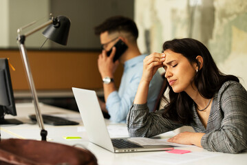 Beautiful businesswoman in office. Tired woman having headache while working..