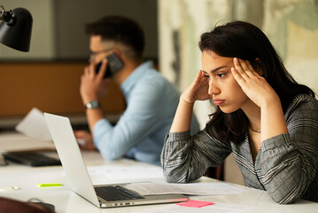 Beautiful businesswoman in office. Tired woman having headache while working..