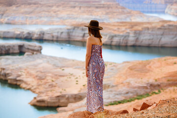 Woman in summer dress wearing a hat on the beach overlooking lake Powell