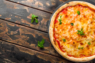 Italian pizza Margherita with cheese, tomato sauce and basil on dark wooden table top view with...