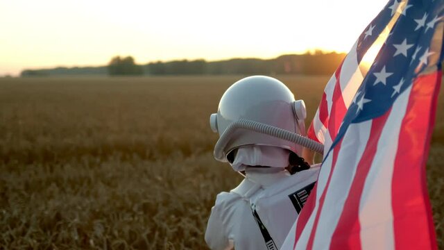Little young happy child boy wearing astronaut uniform and helmet cosmonaut showing american flag of United States, Space man, Kid dream flying, childhood, freedom, travel, future, professions concept