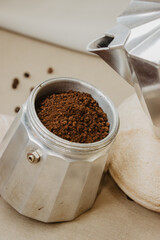 Metal coffee pot with coffee powder on an insulated beige background. Concept coffee 2022.