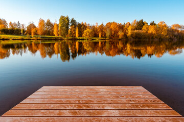 Wooden pier and colorful foliage reflections in lake water