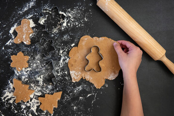 Children's hands make New Year's gingerbread cookies on a wooden table. Making cookies with a cookie cutter. New Year and Christmas concept.