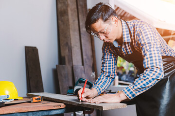 Carpenter working on woodworking machines in carpentry shop.