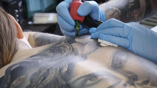 Footage of tattooist making tattoo on female back