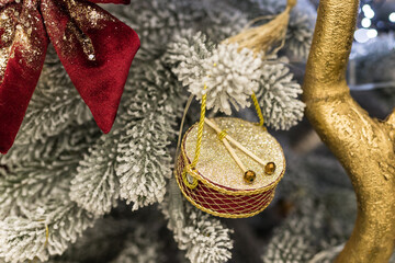 Close up of holidays location with red gold toys, garlands and drum on Christmas tree