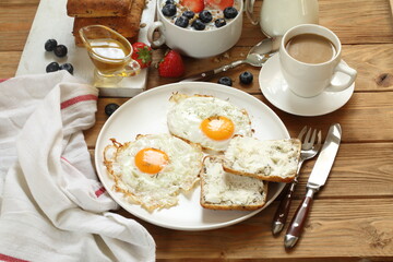 Breakfast with scrambled eggs, muesli with fruits, berries and coffee with milk on a brown wooden background
