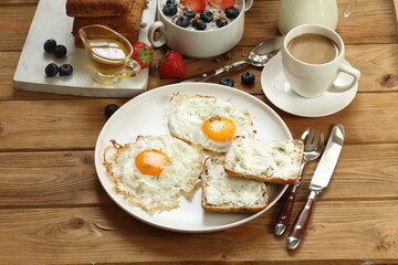 Breakfast with scrambled eggs, muesli with fruits, berries and coffee with milk on a brown wooden background