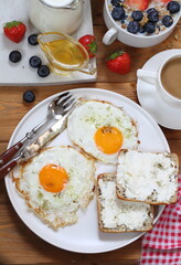 Breakfast with scrambled eggs, muesli with fruits, berries and coffee with milk on a brown wooden background