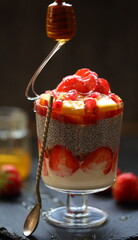 Dessert with chia, yogurt, honey, strawberries, pomegranate on a black background