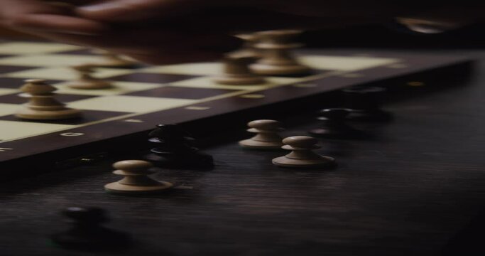 Male hand rearranges the pieces on the chessboard, close-up.