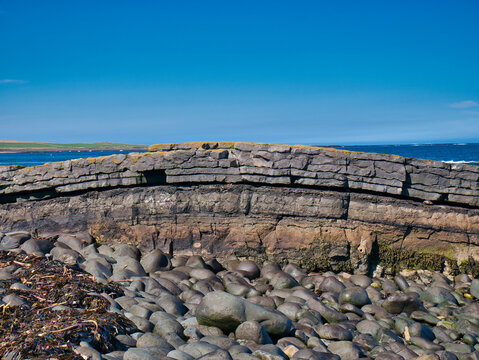 The folded rock strata of Greymare Rock on the Northumberland coast, near Dunstanburgh Castle. An outcrop of the Whin Sill, a tabular layer of the igneous rock dolerite in north east England, UK.
