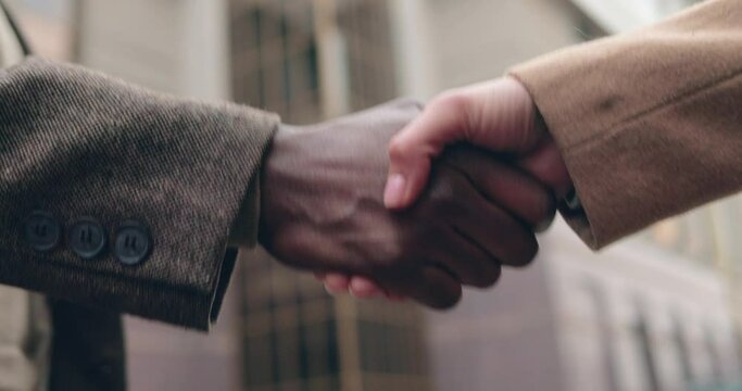 Close up of male hand of african american businessman shaking hands of caucasian female partner in agreement.