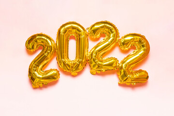 Happy New Year 2022. 2022 golden foil balloons on pink background. Gold helium balloon numbers. Banner