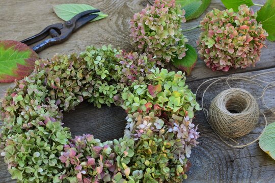 Hydrangea homemade wreath with scissors and rope on  wooden background close up
