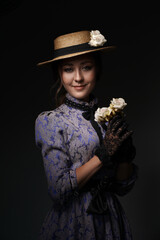 Close-up of a girl standing in a blue dress in the style of the 1900s, in a retro dress, hat and...