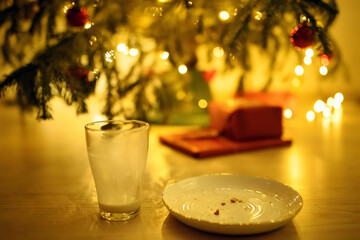 A plate of cookie crumbs and an empty milk glass after a night visit from Santa Claus.