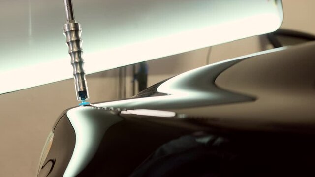 Repairing car dent after the accident by paintless dent repair in car service, using the automatic tool for it.