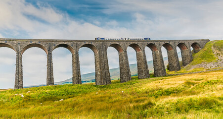 Fototapeta na wymiar A view of a train crossing the Ribblehead Viaduct, Yorkshire, UK in summertime