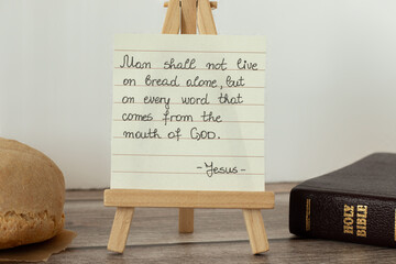 Bread of life and Holy Bible with a handwritten quote. A biblical concept of faith and obedience to...