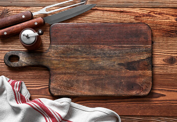 Empty cutting board, salt and pepper, fork and knife on a wood table