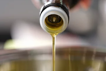 Fototapeten Clear olive oil is poured from dispenser bottle into saucepan closeup © H_Ko