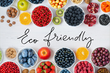 Fresh berries, fruits, nuts on a white wooden background. The concept of healthy eating. Food contains vitamins and trace elements. Eco friendly - handwritten inscription.
