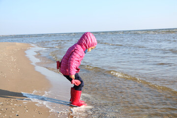 Child girl playing by the sea in autumn.