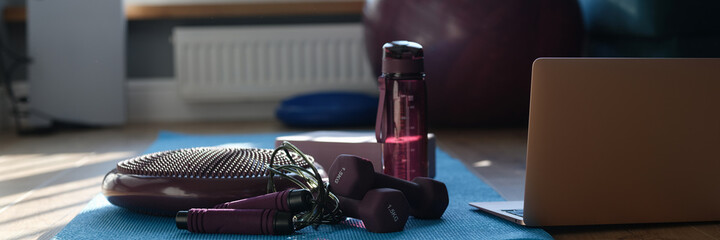 Dumbbell balancing cushion and sports equipment on sports mat with laptop