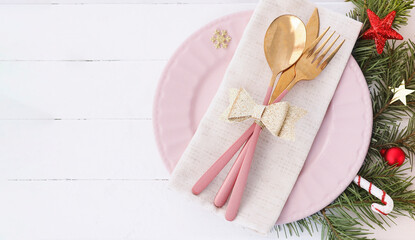 banner of Christmas table setting. pink plate, cutlery with gold bow, fir branches and stars. copy space..
