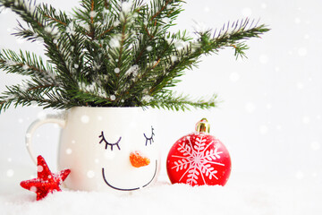 card snowy fir branches in a cup with the face of a sleeping snowman, a red Christmas ball and a star on a white background..