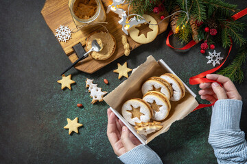 Preparing a homemade sweet present. Linzer Christmas or New Year cookies filled with peanut butter on a dark stone tabletop. Top view flat lay background. Copy space.