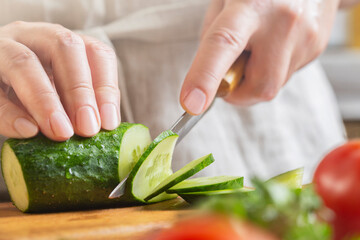 Chef slicing cucumber on the table in restaurant. Process of cutting vegetables in kitchen.