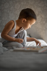 a little boy at home flips through a book and looks at pictures