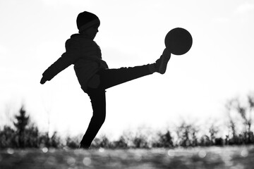 Naklejka premium Silhouette of young boy playing football