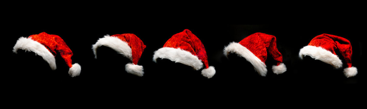 Rote Weihnachtsm&uuml;tzen isoliert vor schwarzem hintergrund