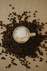 Still Life of cup of coffee at the bottom of the coffee beans on brown background.