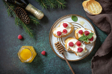 Christmas dinner, holiday menu. Traditional italian antipasto bruschetta appetizer with cream cheese, raspberries and honey is served on a festive xmas table. Top view flat lay.