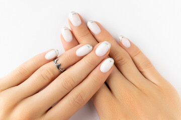 Beautiful groomed womans hands with modern french nail design on white