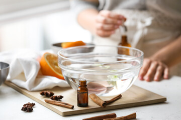 Bottle of essential oil with spices and bowl with water on table