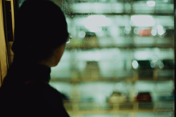 Girl Looking Thoughtfully Through Window with Futuristic City Lights