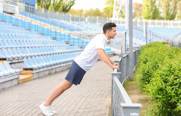 Sporty young man doing push ups at stadium